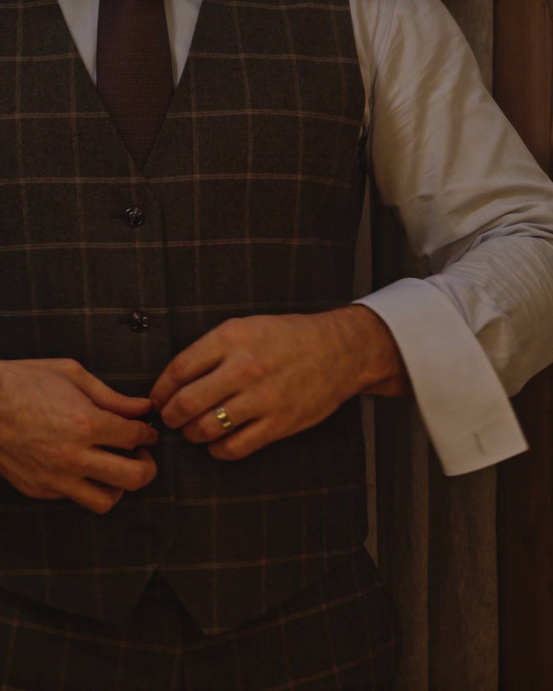 Chaleco a cuadros con corbata bordó y gemelos en los puños.