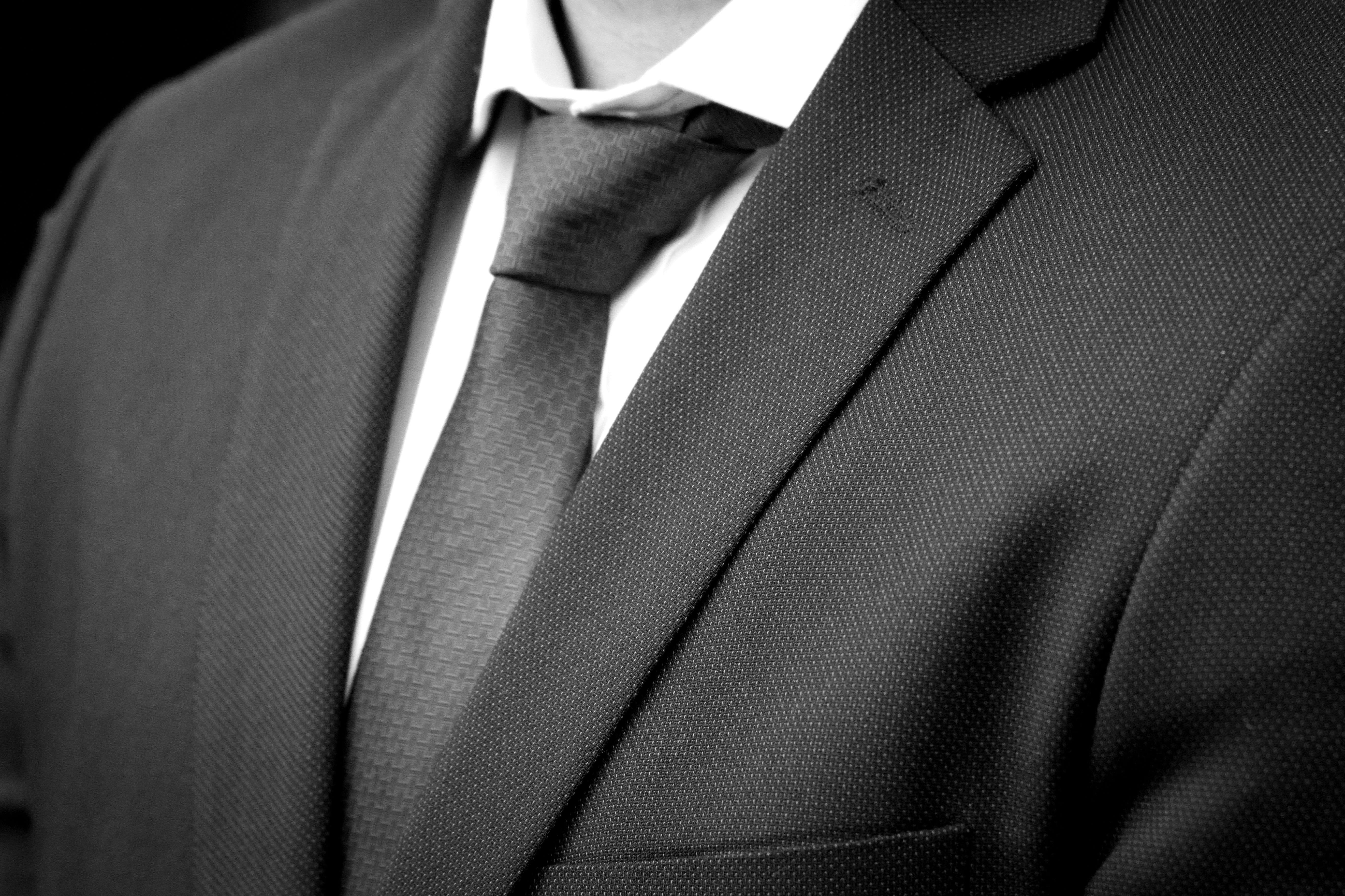 Saco gris carbón con tejido ojo de perdiz, corbata de jacquard y camisa blanca, en primer plano.